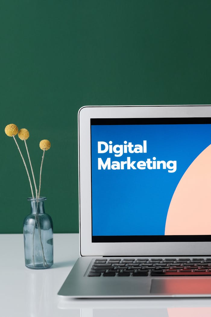 why-choose-us A laptop displaying 'Digital Marketing' with a minimalist floral decor in a glass vase.