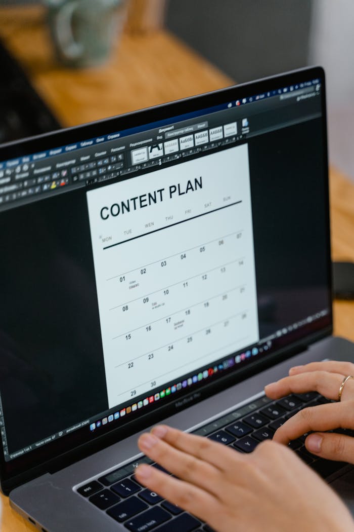 about-02 Close-up of hands typing on a laptop displaying a content plan document, ideal for business or marketing content.